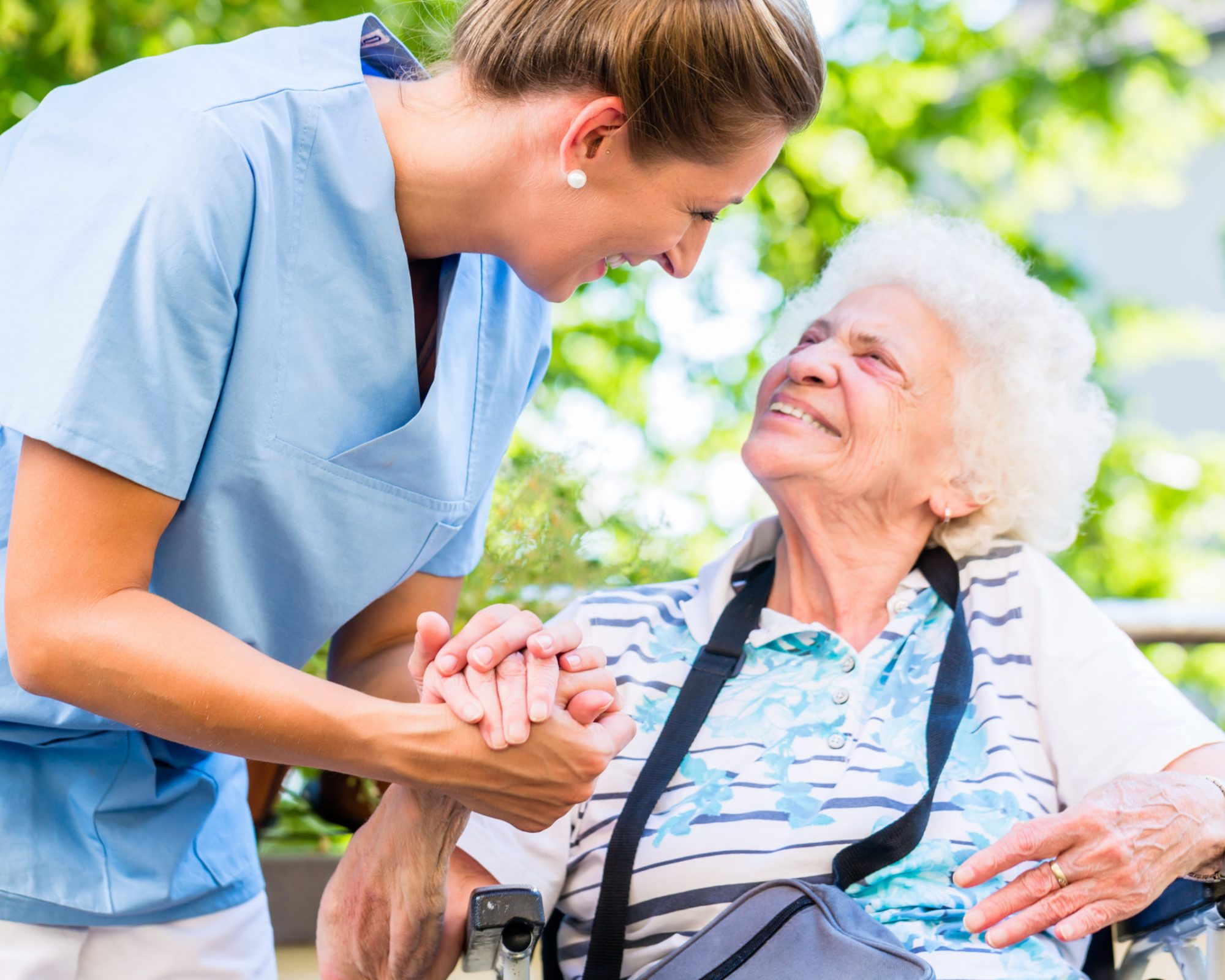 Nurse holding hand of senior woman in pension home