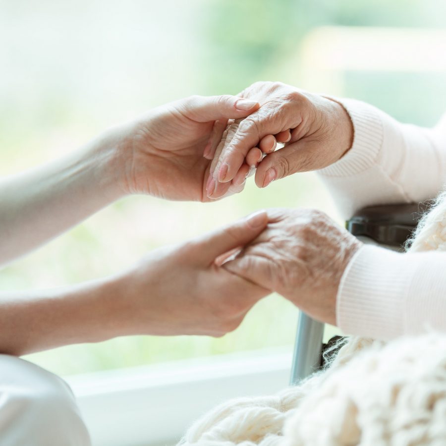 Photo of nurse holding her woman patient's hands with painted nails